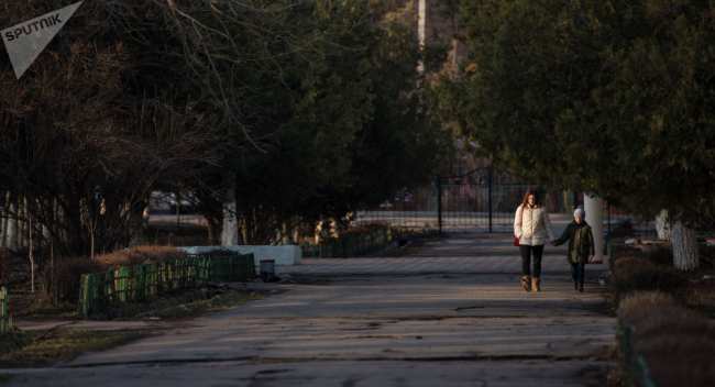 Женщина с ребенком идут по аллее в одном из микрорайонов Бишкека. Архивное фото