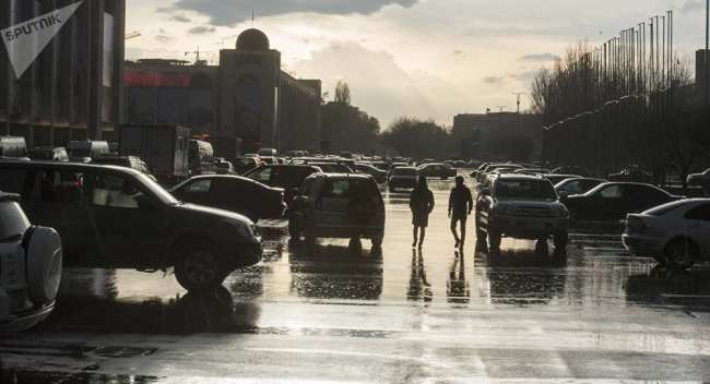 Горожане идут по площади Ала-Тоо в Бишкеке после дождя. Архивное фото